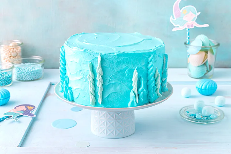 Vorbereitung verschiedener Blautöne der Schlagcreme in Schälchen, um Korallen und Unterwasserpflanzen für die Meerjungfrauen-Torte zu gestalten