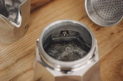 Vorgeheiztes Wasser wird in den Espressokocher gefüllt