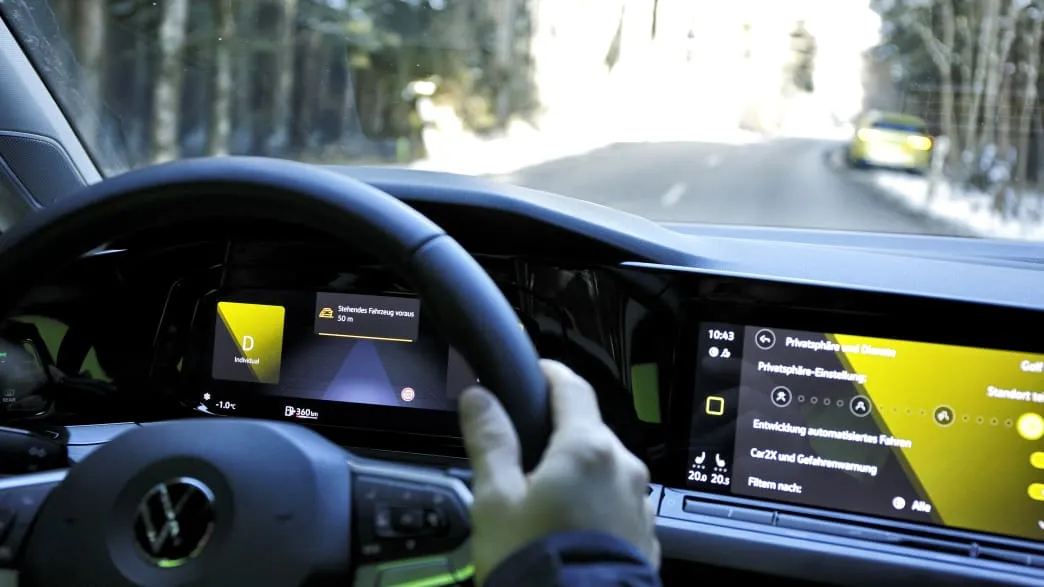 VW Golf 8 nähert sich einem Pannenfahrzeug hinter einer Kurve dank Car2X-Warnung