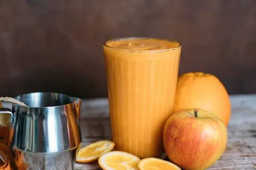 Warmer Smoothie mit Karotte, Ingwer und Orange in einem Glas, garniert mit Minze.