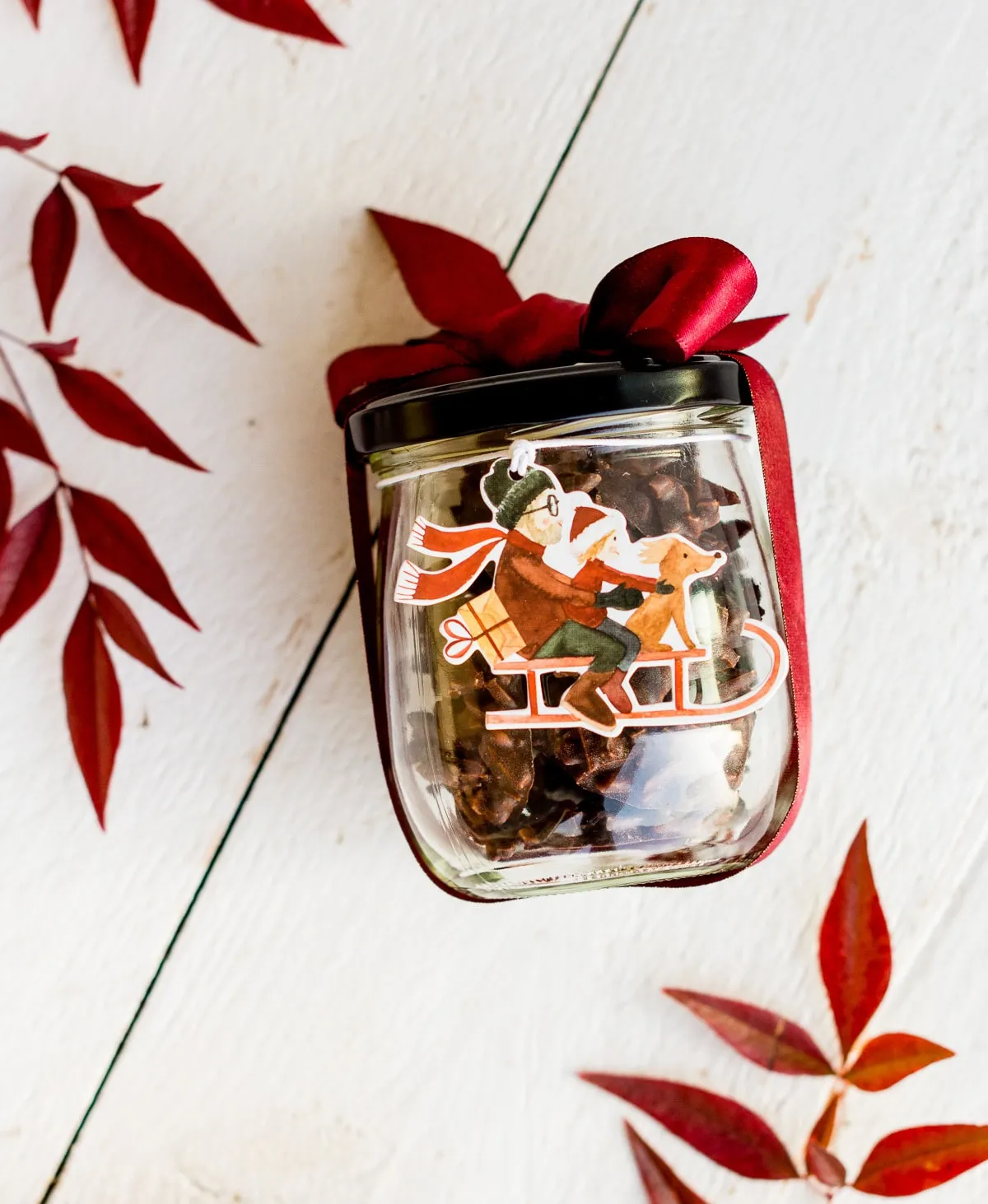 Weihnachtlich dekoriertes Glas gefüllt mit dunklen Mandelsplittern