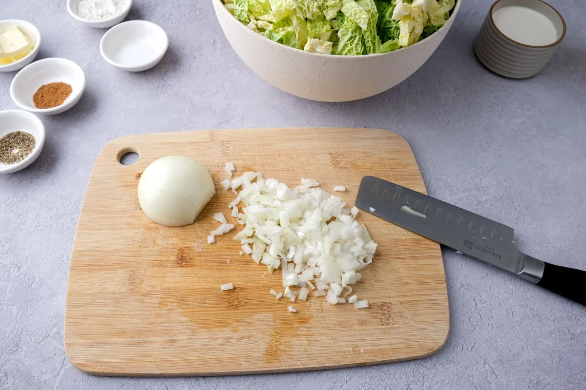 Weiße Zwiebel auf Holzschneidebrett mit Messer daneben