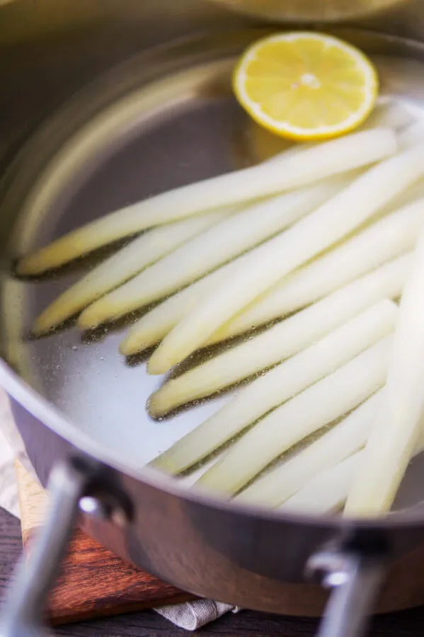 Weißer Spargel mit Zitrone in einem Kochtopf während des Garvorgangs