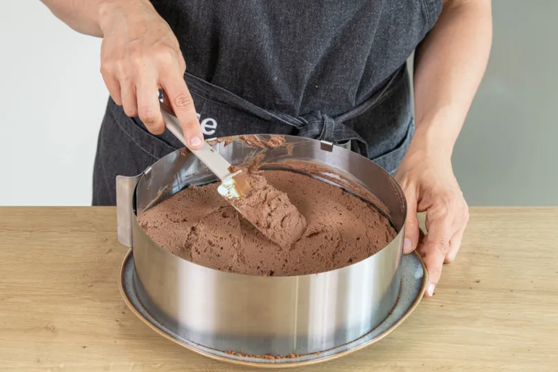 Weitere Schokosahne wird auf den mittleren Boden gestrichen