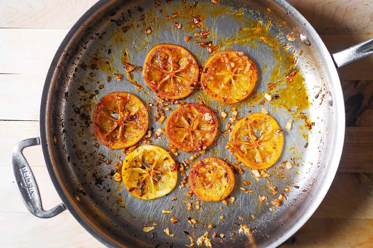 Zarte Zitronenscheiben und gehackter Knoblauch, leicht angebraten in Butter in einer Pfanne, als Basis für die Soße.