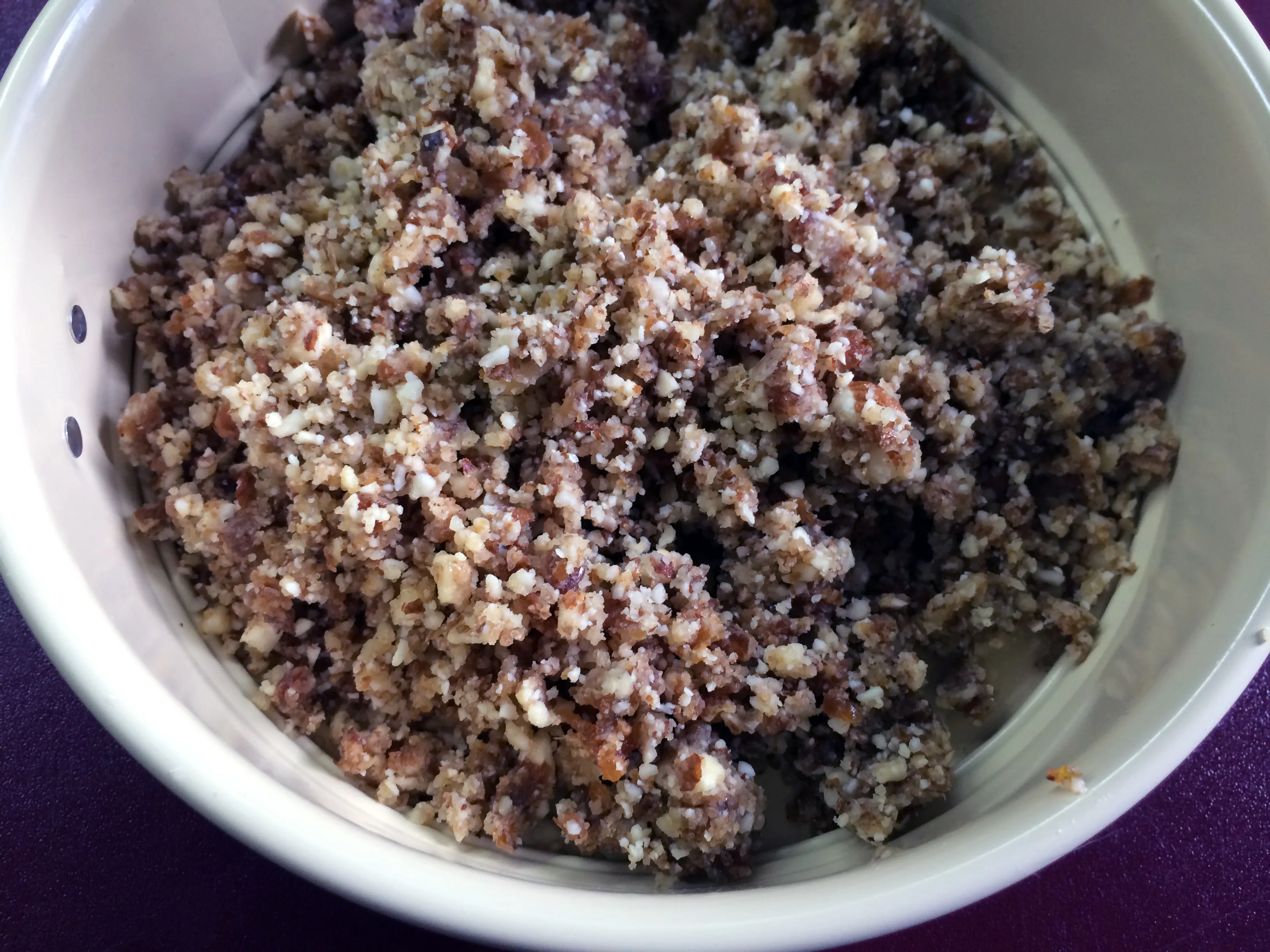 Zerkleinerte Nuss-Dattel-Mischung als fester Kuchenboden in der Springform