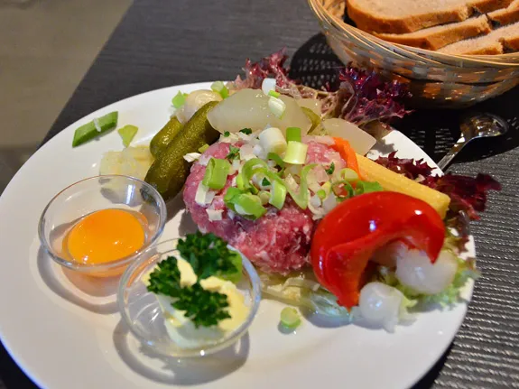 Zubereitetes Schweinemett (Schweinetatar) mit reichlich eingelegtem Gemüse, servierfertig zum Bestreichen von Brot