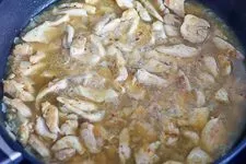 Zubereitung der Currysoße mit Hühnerbrühe und Sahne in der Pfanne