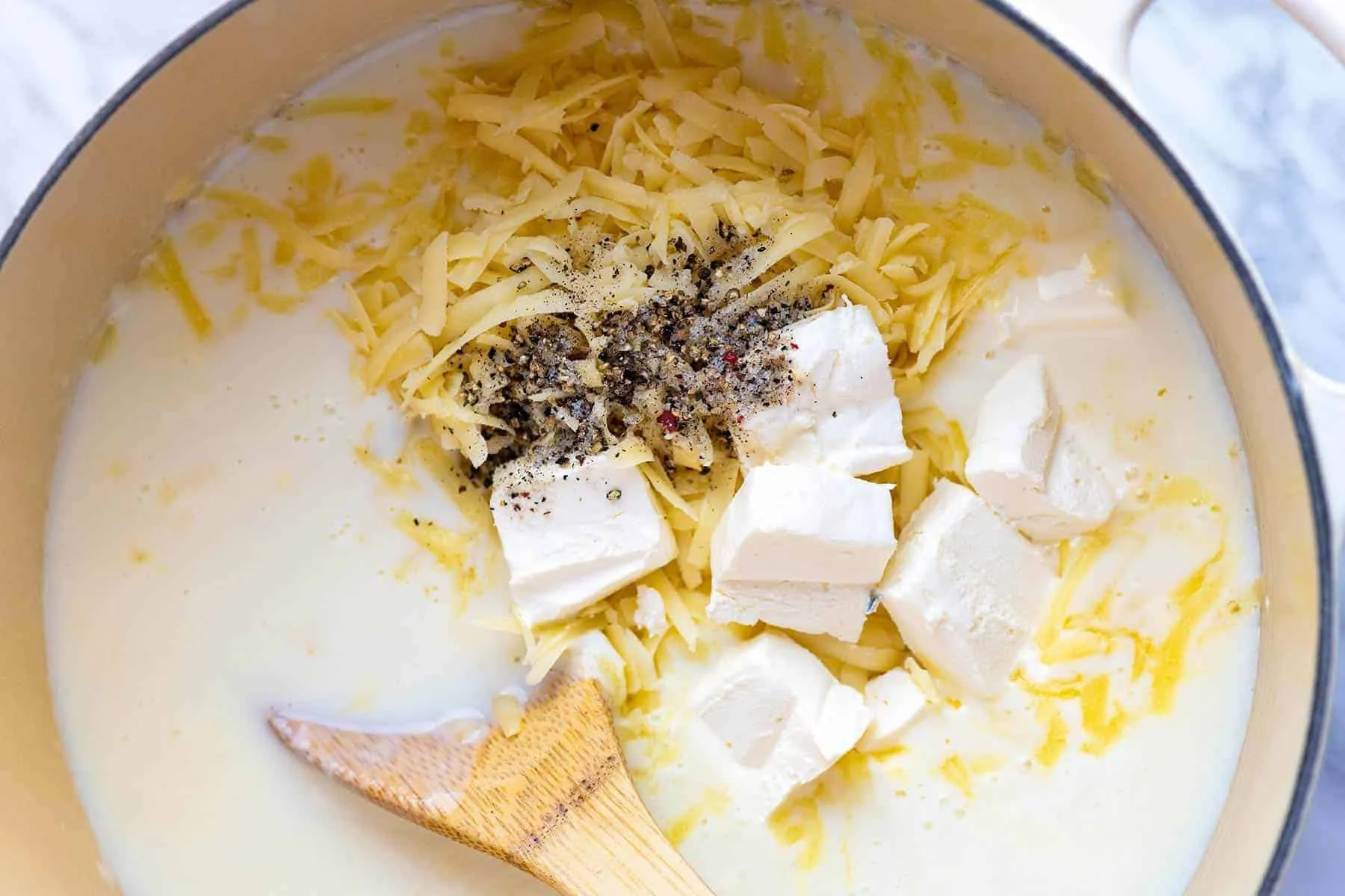 Zubereitung der Käsesauce mit Cheddar, Frischkäse und Milch für cremiges Mac and Cheese.