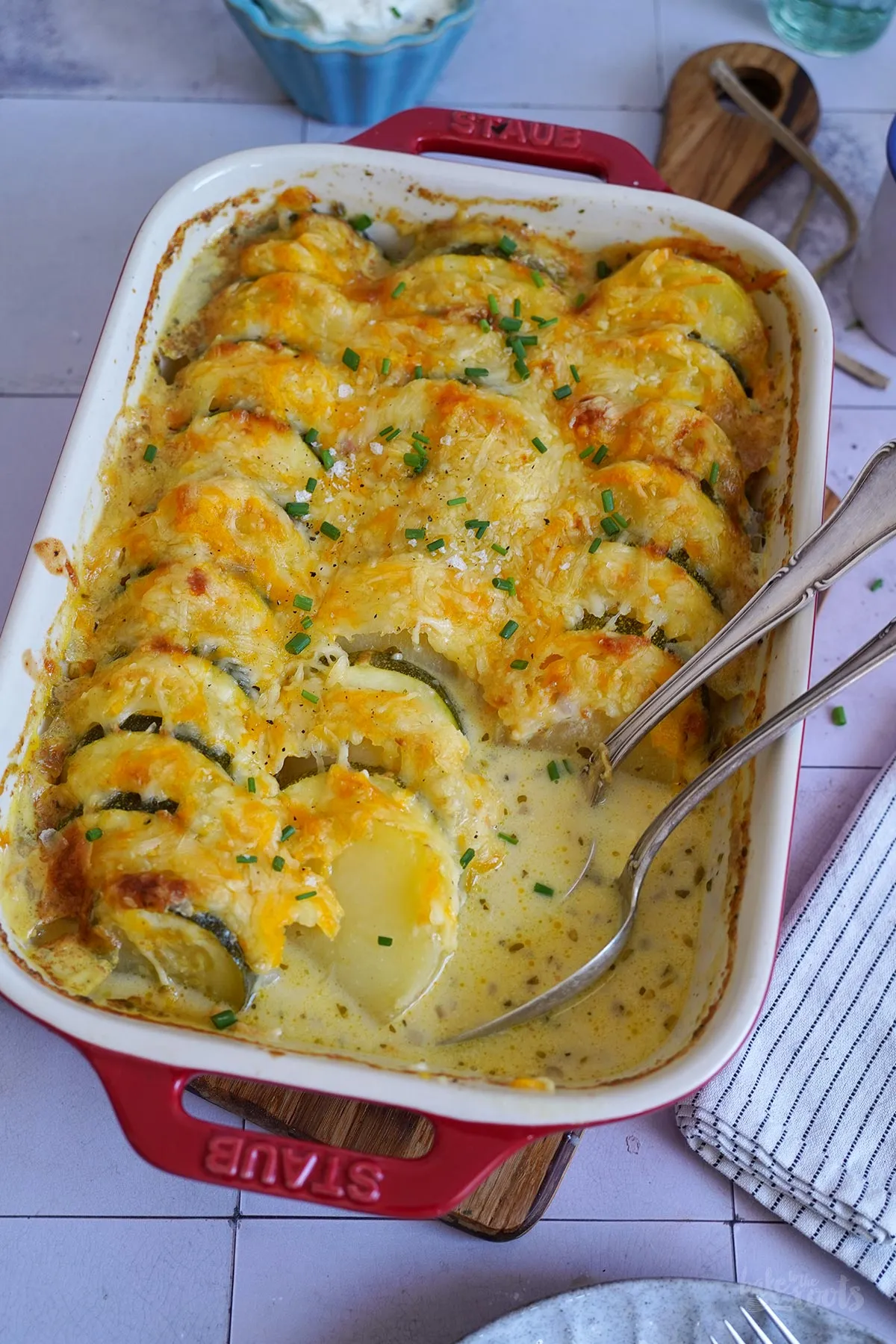 Zucchini-Kartoffel-Auflauf goldbraun gebacken, mit geschmolzenem Käse und frischen Kräutern