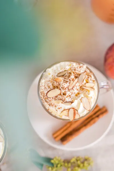 Zutaten für Bratapfelpunsch: Apfel, Gewürze wie Zimtstangen, Sternanis und Nelken auf einem Holztisch.