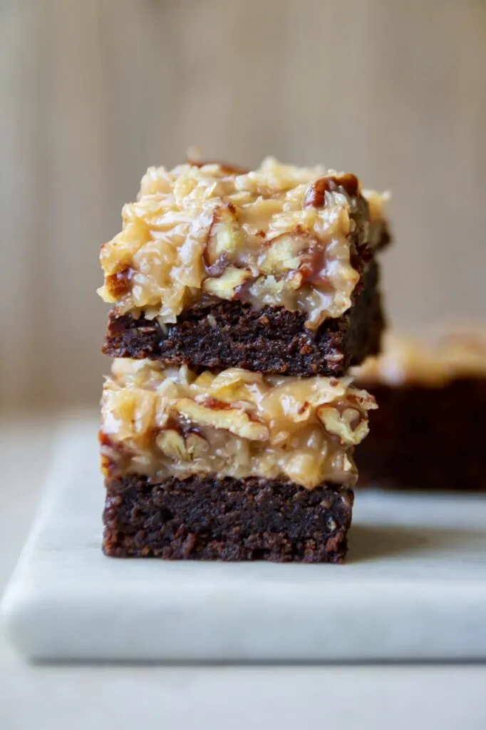 Zutaten für das vegane Brownie Rezept, darunter vegane Kondensmilch, Pekannüsse und Kokosraspeln, auf einem Küchentisch arrangiert.