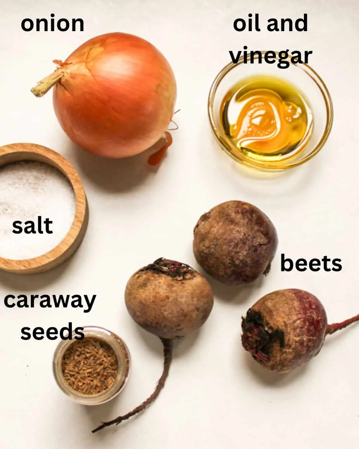 Zutaten für deutschen Rote Bete Salat: Rote Bete, Zwiebel, Essig, Öl, Salz und Kümmel auf weißem Hintergrund.