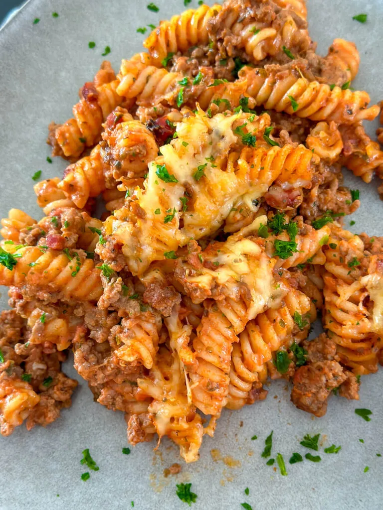 Zutaten für einen schnellen Nudel-Hackfleisch-Auflauf: Nudeln, Hackfleisch, Tomaten und Kräuter auf einer Küchenzeile arrangiert.