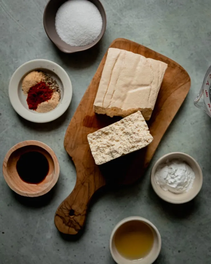 Zutaten für knusprige Kartoffelspalten: Kartoffeln, Speisestärke, Öl und Gewürze bereitgelegt.