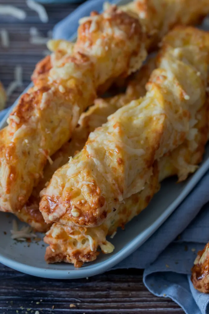 Zutaten für schnelle Käsestangen, darunter geriebener Käse und Mehl, für ein unkompliziertes herzhaftes Gebäck.