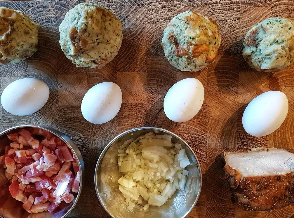 Zutaten für Tiroler Gröstl: geschnittener Speck, Zwiebelringe, Knödelscheiben und Schweinebratenwürfel