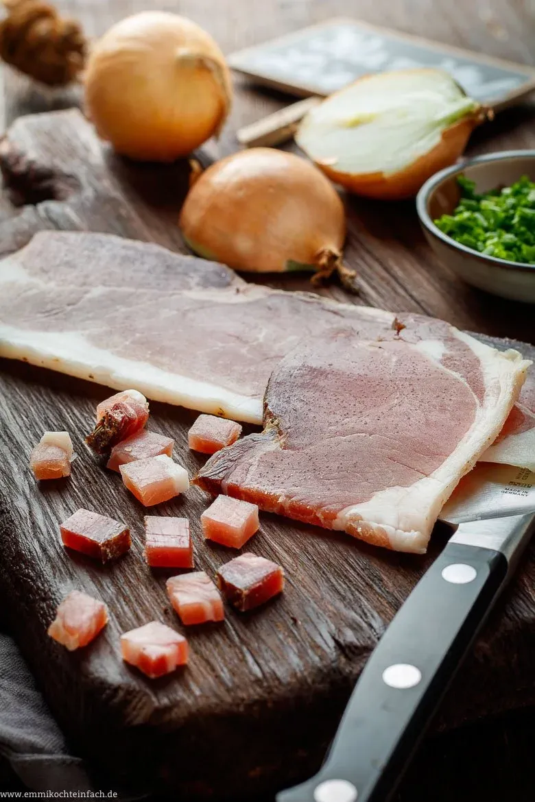 Zutaten: Speckwürfel und geschnittene Zwiebeln für Bratkartoffeln