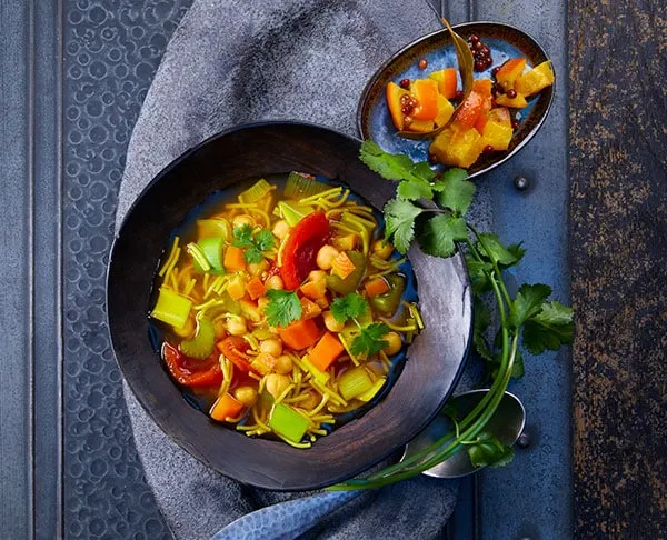 Zwei aromatische Suppen in Schalen, darunter Harira und Paprika-Ingwer-Curry Suppe