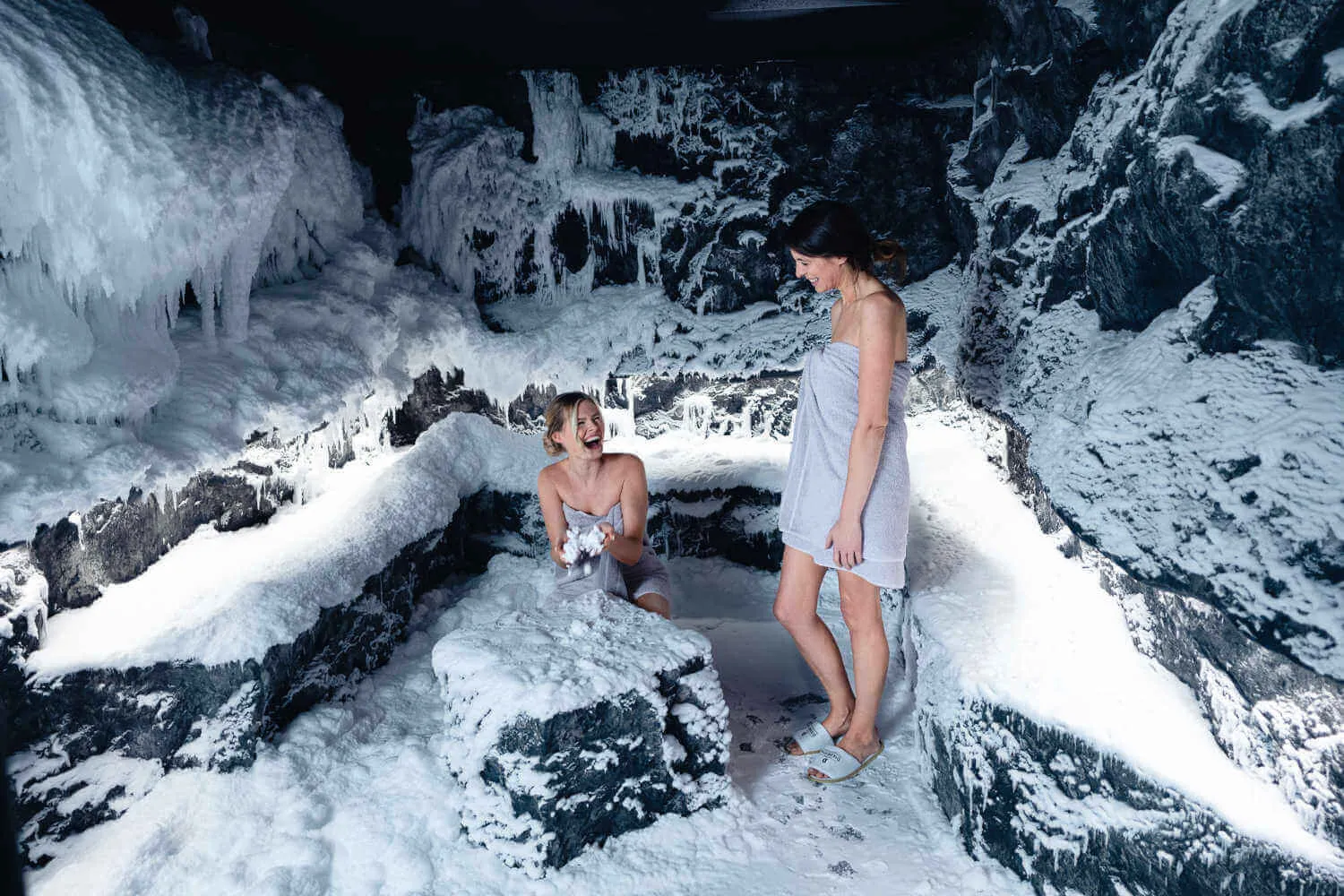Zwei Freudinnen haben Spaß in der Schneegrotte und spielen mit dem Schnee.