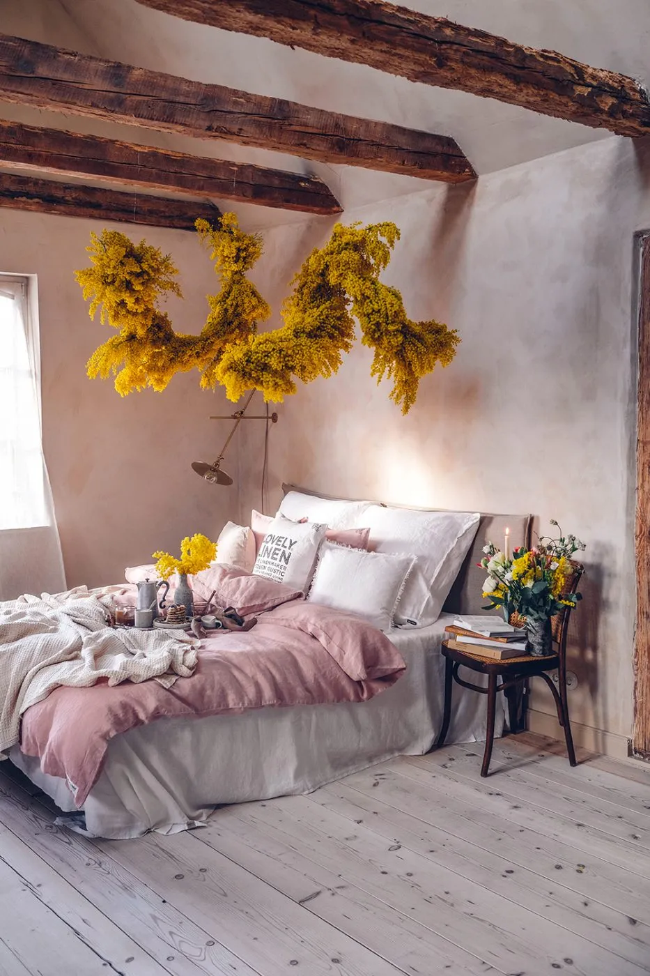 Zwei Hände reichen nach Heidelbeer-Pancakes auf einem Bett mit rosa Leinen