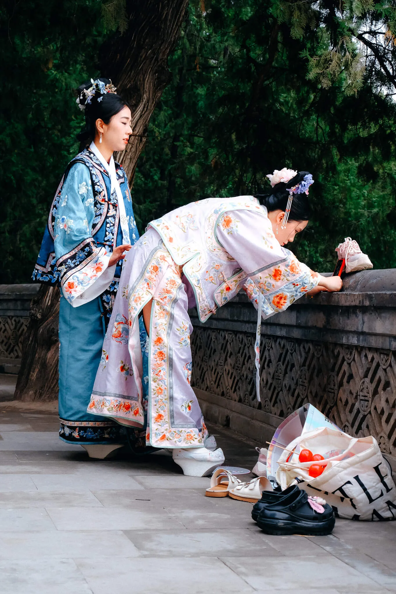 Zwei junge Frauen in historischer chinesischer Hanfu-Kleidung machen eine TikTok-Aufnahme mit einem Smartphone vor einer traditionellen chinesischen Kulisse.