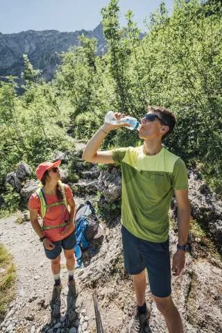 Zwei junge Wanderer machen Pause und trinken Wasser