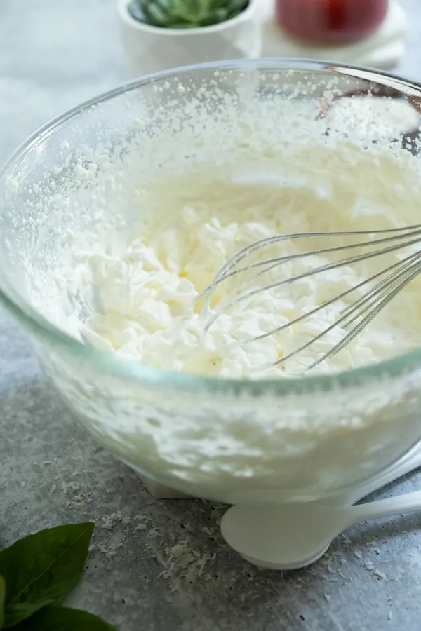 Zwei Kugeln Vanilleeis in einer Kartoffelpresse, bereit für die Zubereitung von Spaghettieis