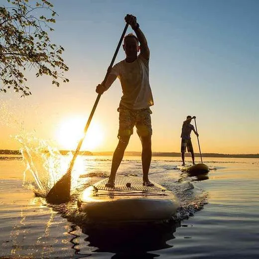 Zwei Männer beim Stand-up-Paddling auf einem ruhigen See bei Sonnenuntergang in der deutschen Natur