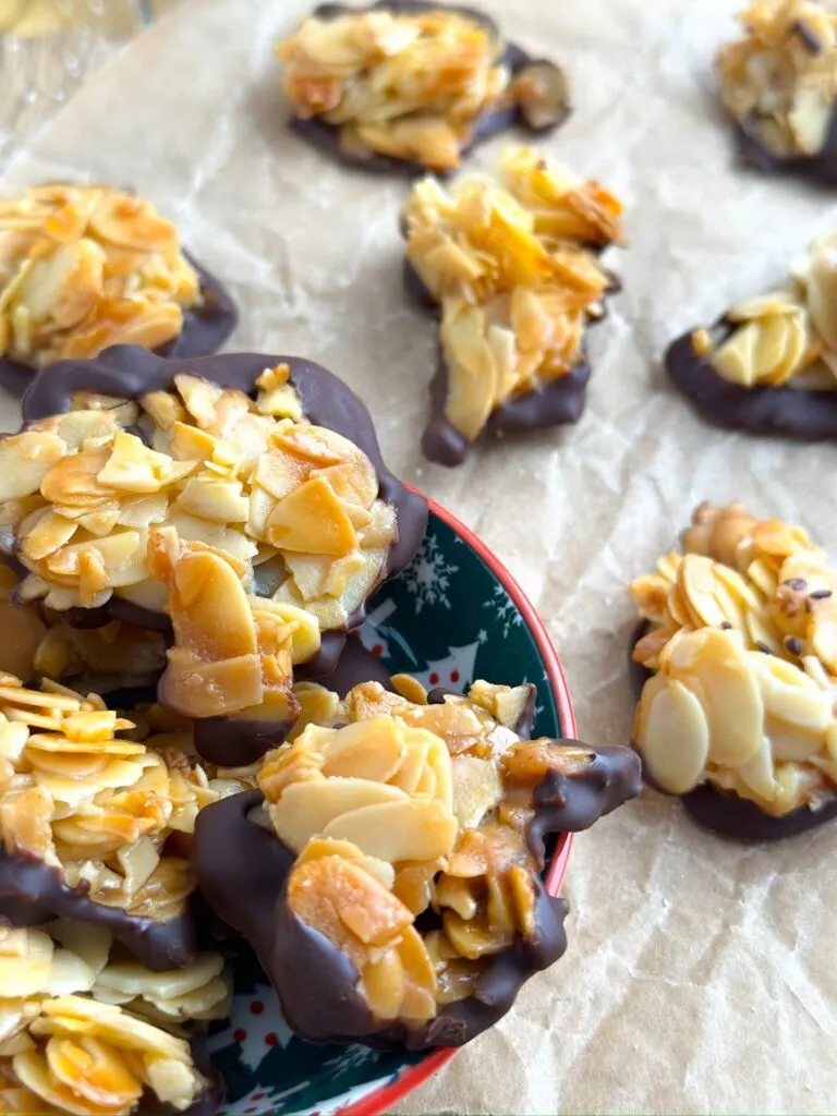 Zwei perfekt gebräunte Florentiner Plätzchen, die ihre karamellisierte Textur und den Glanz der Schokolade zeigen, bereit zum Genießen als weihnachtliches Gebäck.