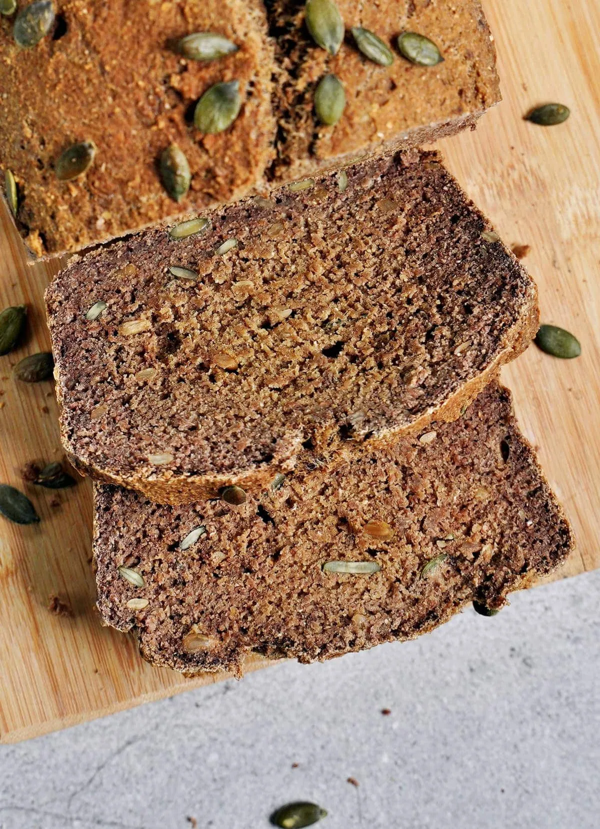 Zwei Scheiben unseres gesunden veganen Linsenbrots mit Kürbiskernen auf einem Holzbrett, ideal für den Start in den Tag.
