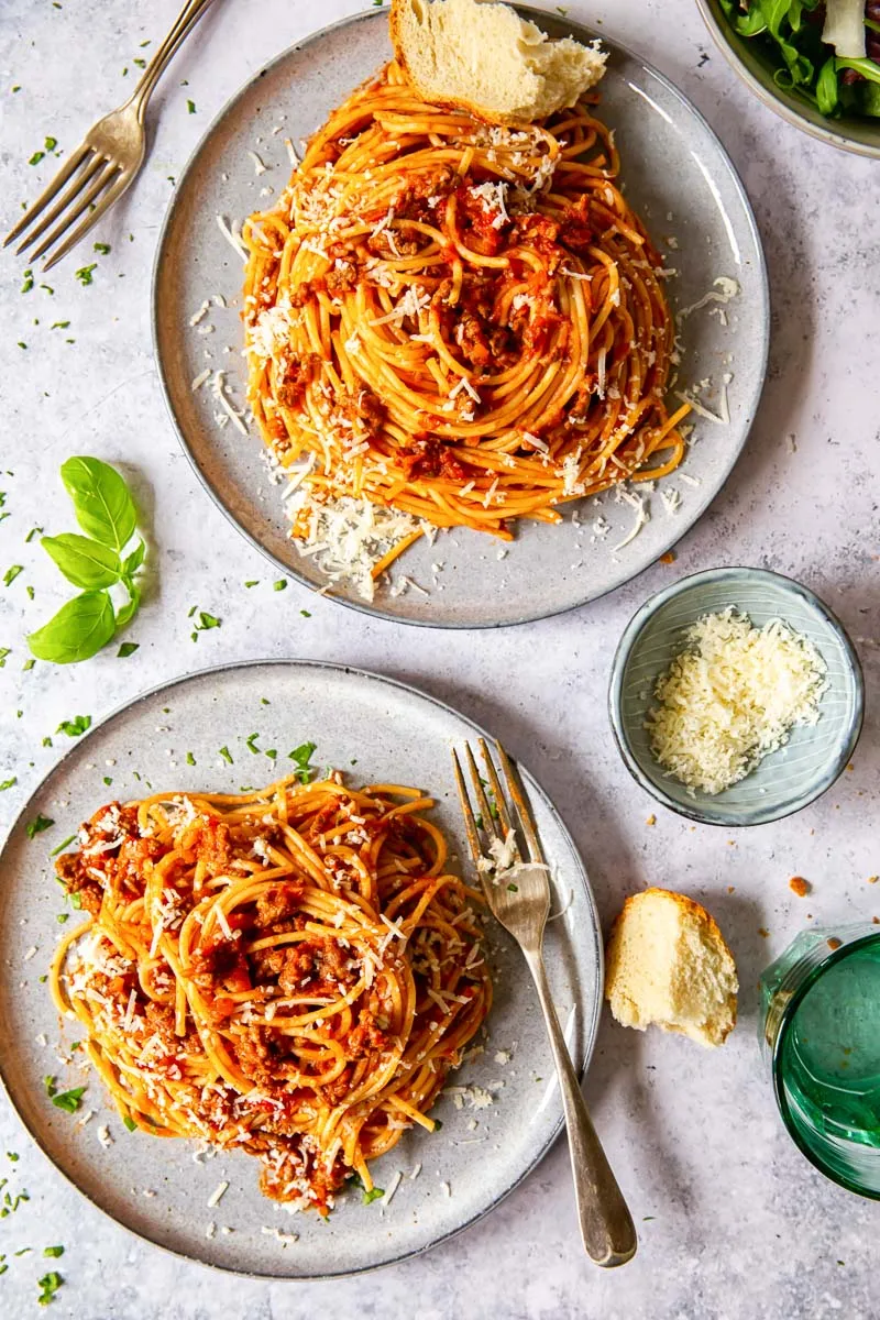Zwei Teller Spaghetti Bolognese, von oben fotografiert, angerichtet für ein Familienessen.