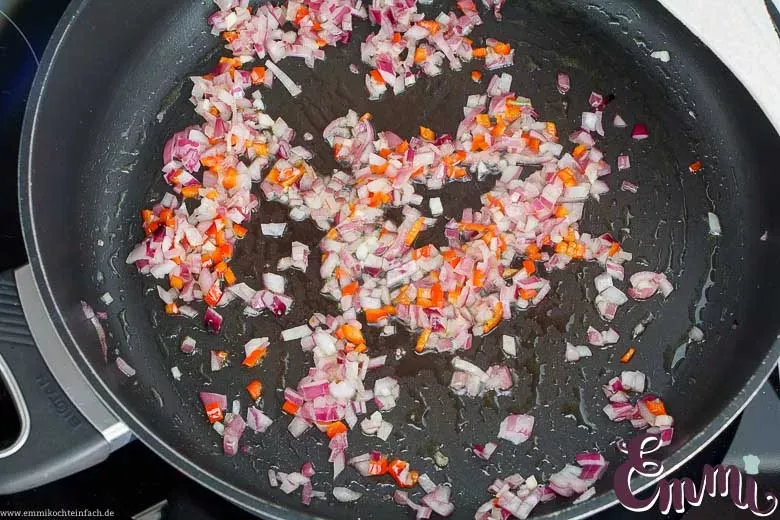 Zwiebeln, Knoblauch und Peperoni in einer Pfanne andünsten für die Mozzarella-Tomaten-Soße.