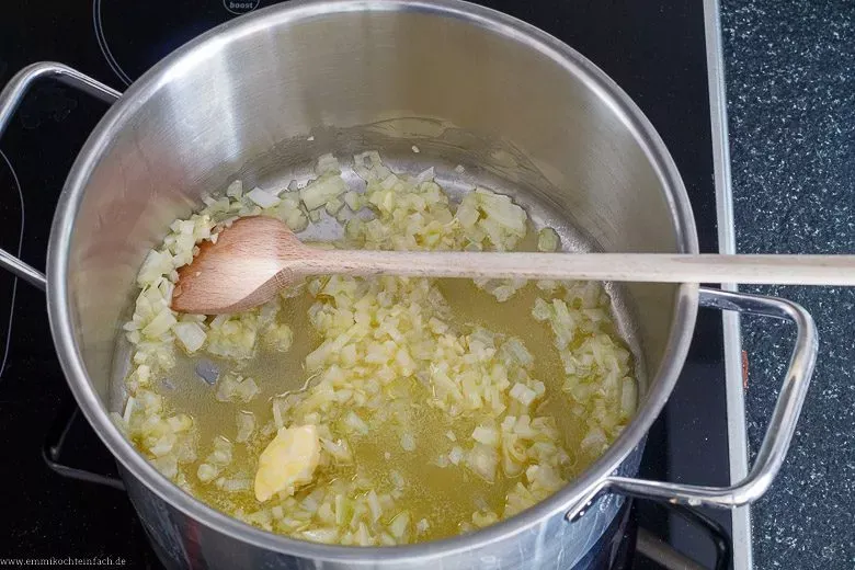 Zwiebeln und Knoblauch werden in Butter in einem Topf angedünstet, ein wichtiger Schritt beim Suppe kochen für Anfänger, um Aroma zu entfalten.