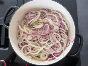 Zwiebeln und Speck, die in einer Pfanne angebraten werden, während der Zubereitung von Zwiebelkuchen