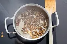 Zwiebeln und Steinpilze werden in Butter und Öl in einem Topf angedünstet.