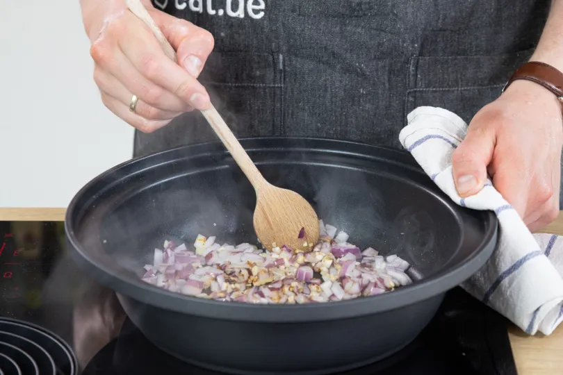 Zwiebeln werden in einer traditionellen Tajine angebraten