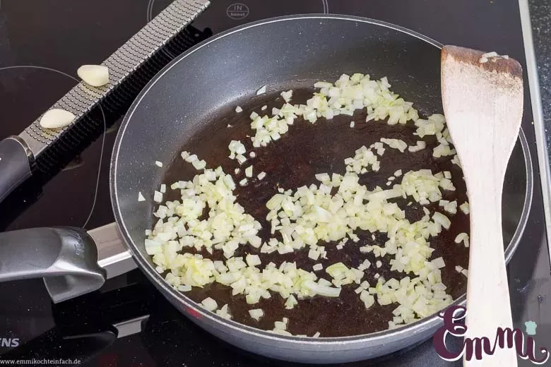 Zwiebelwürfel und Knoblauch werden in Olivenöl angedünstet, um die Basis für die geschmackvolle Zucchini Hackfleisch Füllung zu legen.