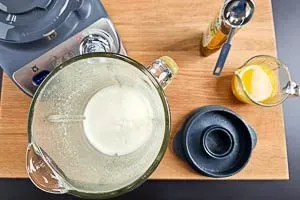 Alle Ingwer-Shot-Zutaten, inklusive frischem Ingwer, Zitronen- und Orangensaft sowie Agavendicksaft, werden in einem Mixer püriert