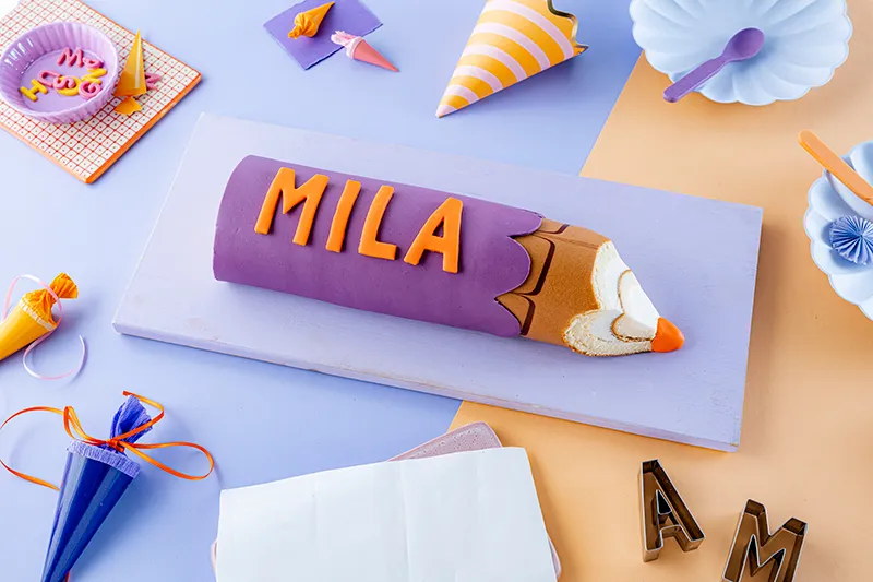 Anbringen der Namensbuchstaben auf dem Buntstiftkuchen.