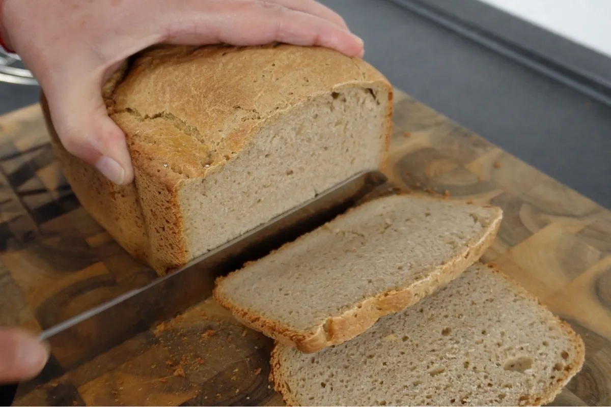 Angeschnittenes Roggenmischbrot aus dem Brotbackautomaten auf einem Holzbrett mit einem Messer