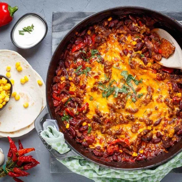 Anrichte einer Tex Mex Steak Pfanne mit Beilagen wie Tortillas und Creme Fraiche