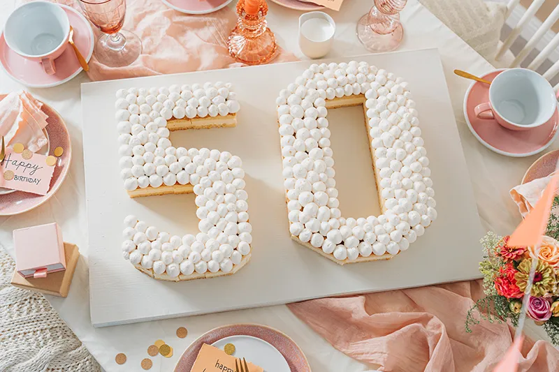 Anwendung von Sahnetupfern auf dem Zahlenkuchen mit einem Spritzbeutel