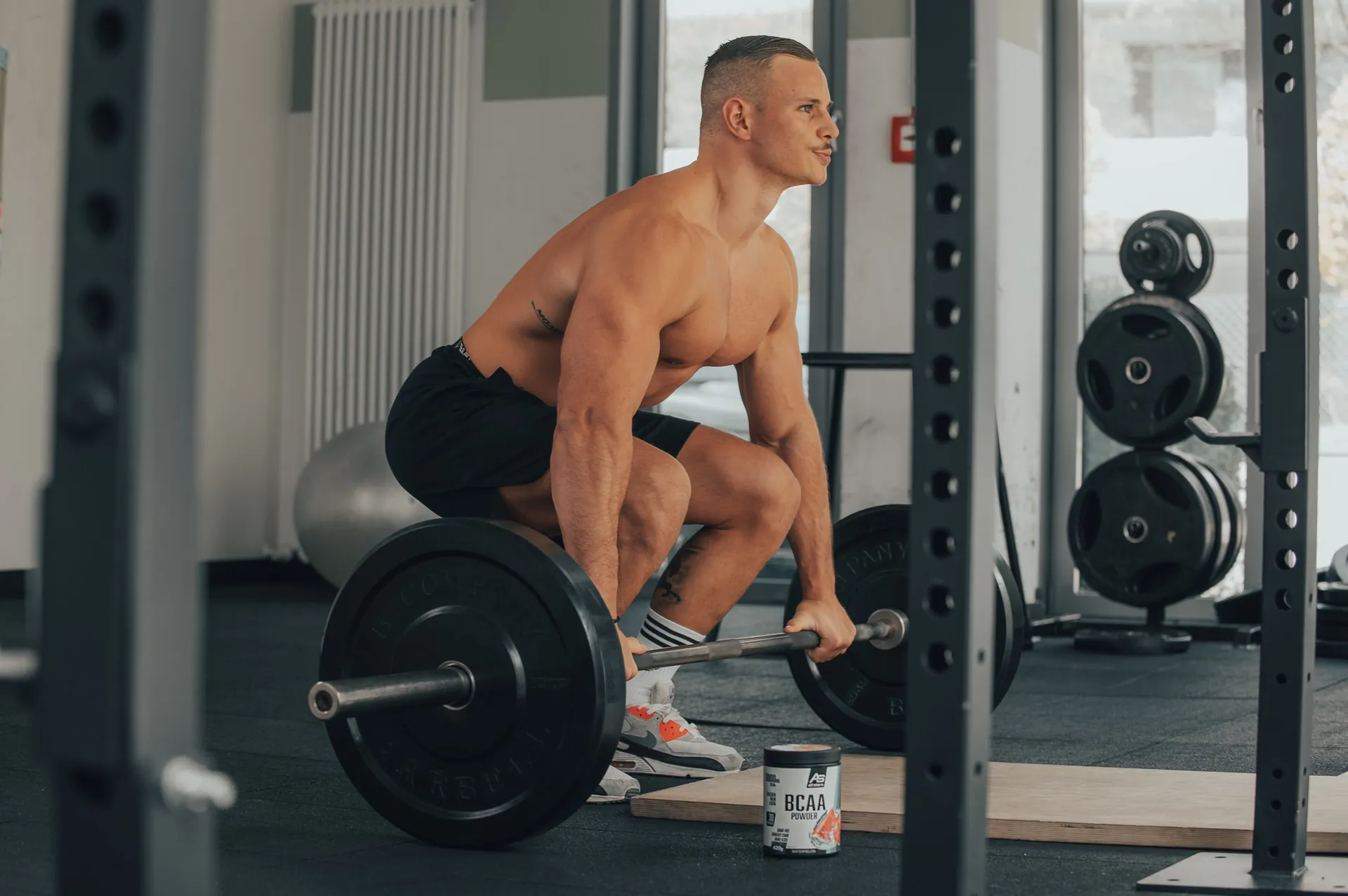 Athlet mit Zughilfen bereitet sich auf Kreuzheben mit einer Langhantel im Fitnessstudio vor