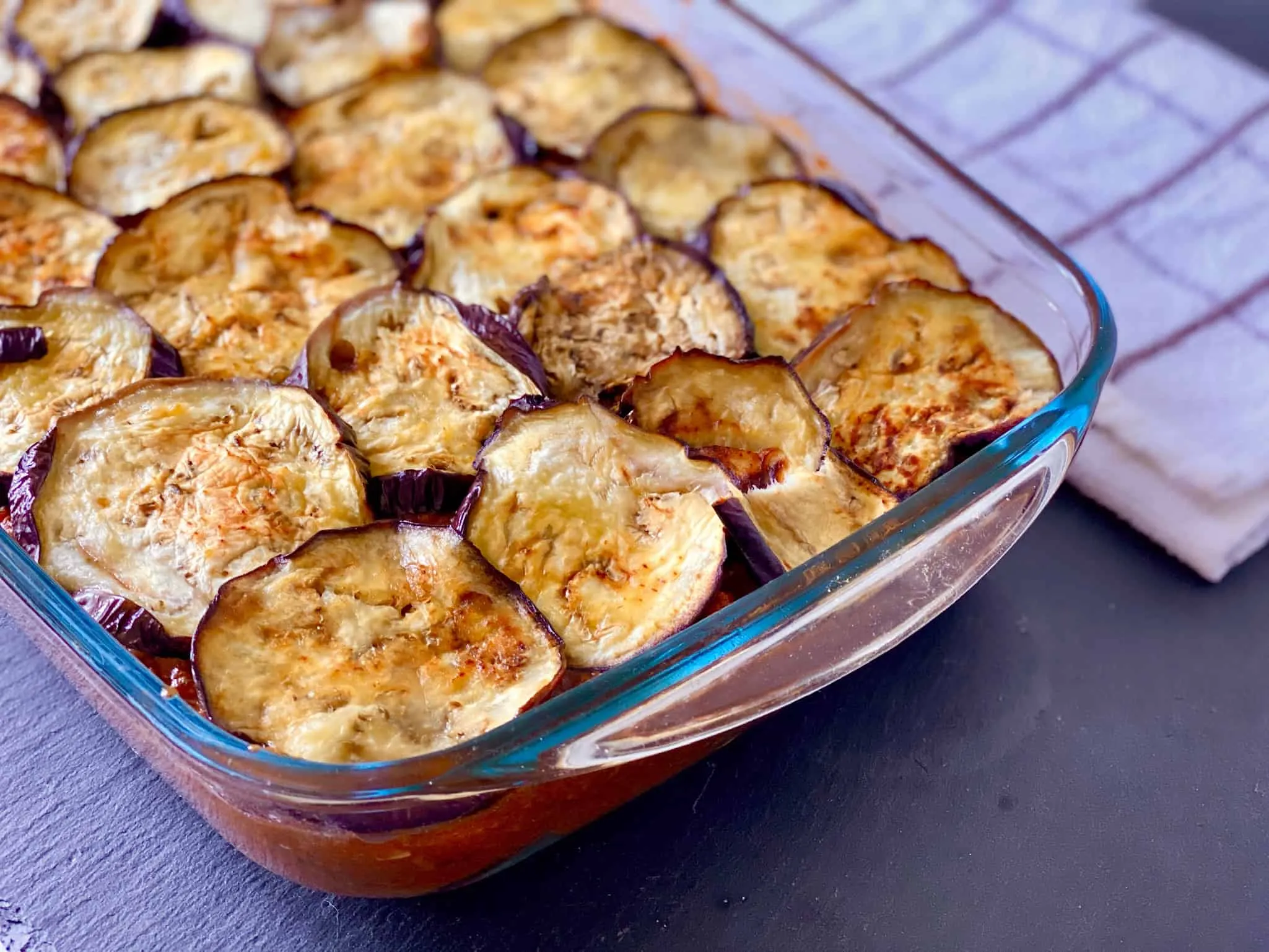 Auberginenscheiben werden sorgfältig für die Schichtung des Moussaka ausgelegt, bereit für den Auflauf