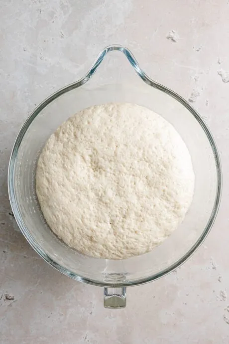 Aufgegangener Hefeteig in einer Glasschüssel, bereit zur Weiterverarbeitung