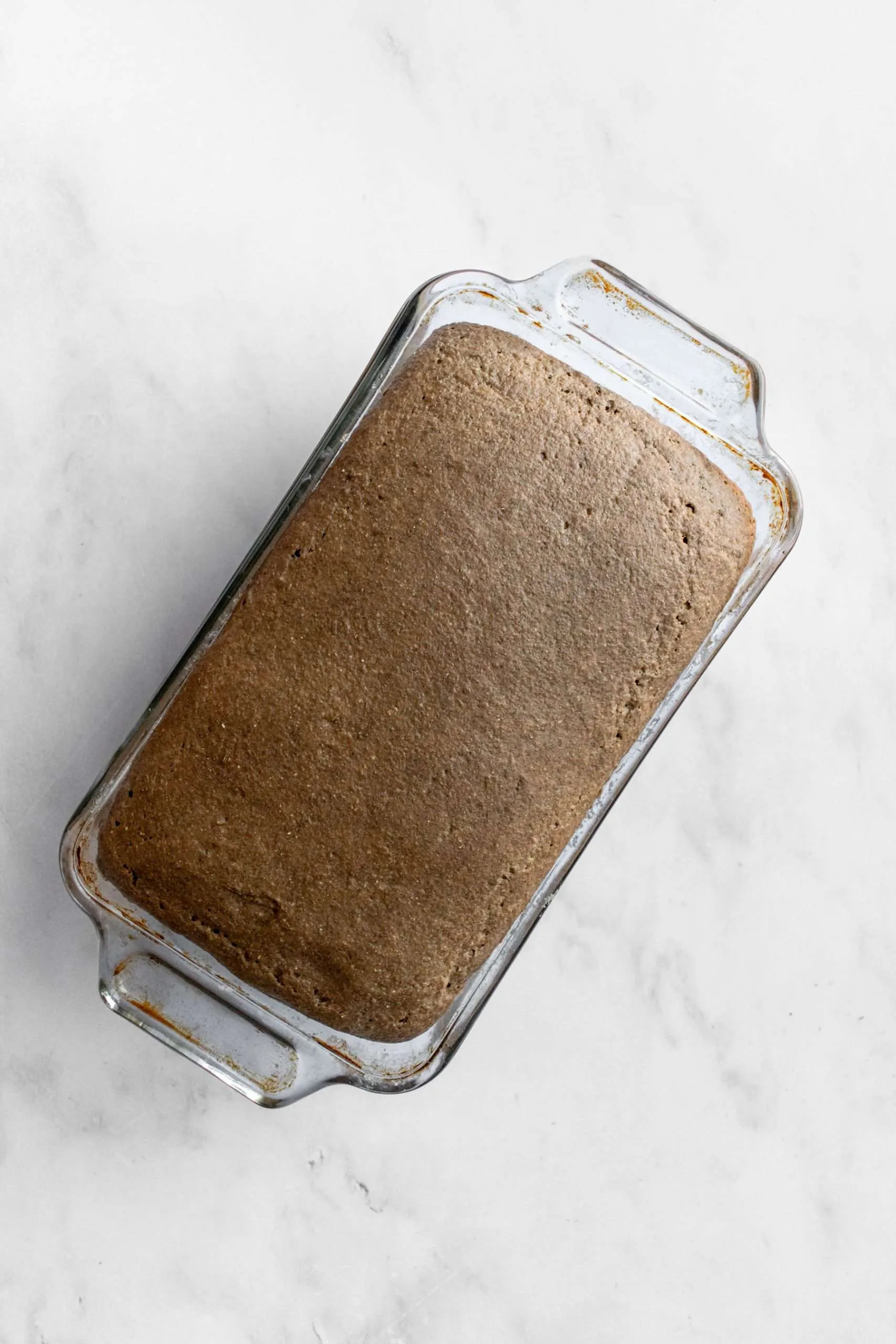 Aufgegangener Schwarzbrot-Teig in einer Glas-Kastenform.