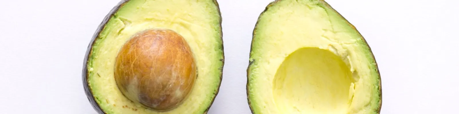 Avocados auf einem rustikalen Holztisch, daneben ein Messer