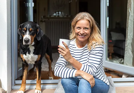 Best Ager mit Hund genießt den Morgenkaffee auf dem Balkon.
