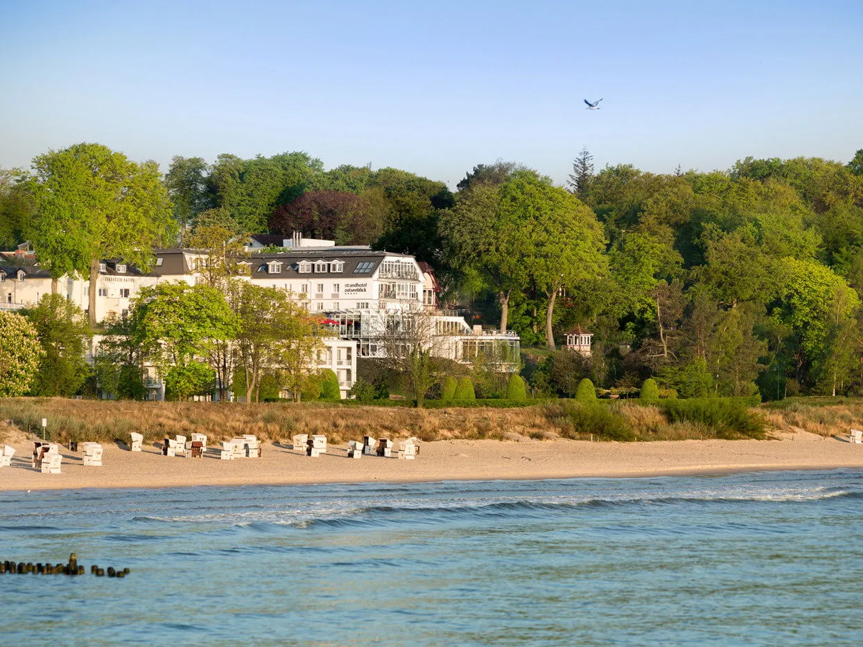 Blick auf die Ostsee mit einem Strandhotel im Hintergrund und blauem Himmel